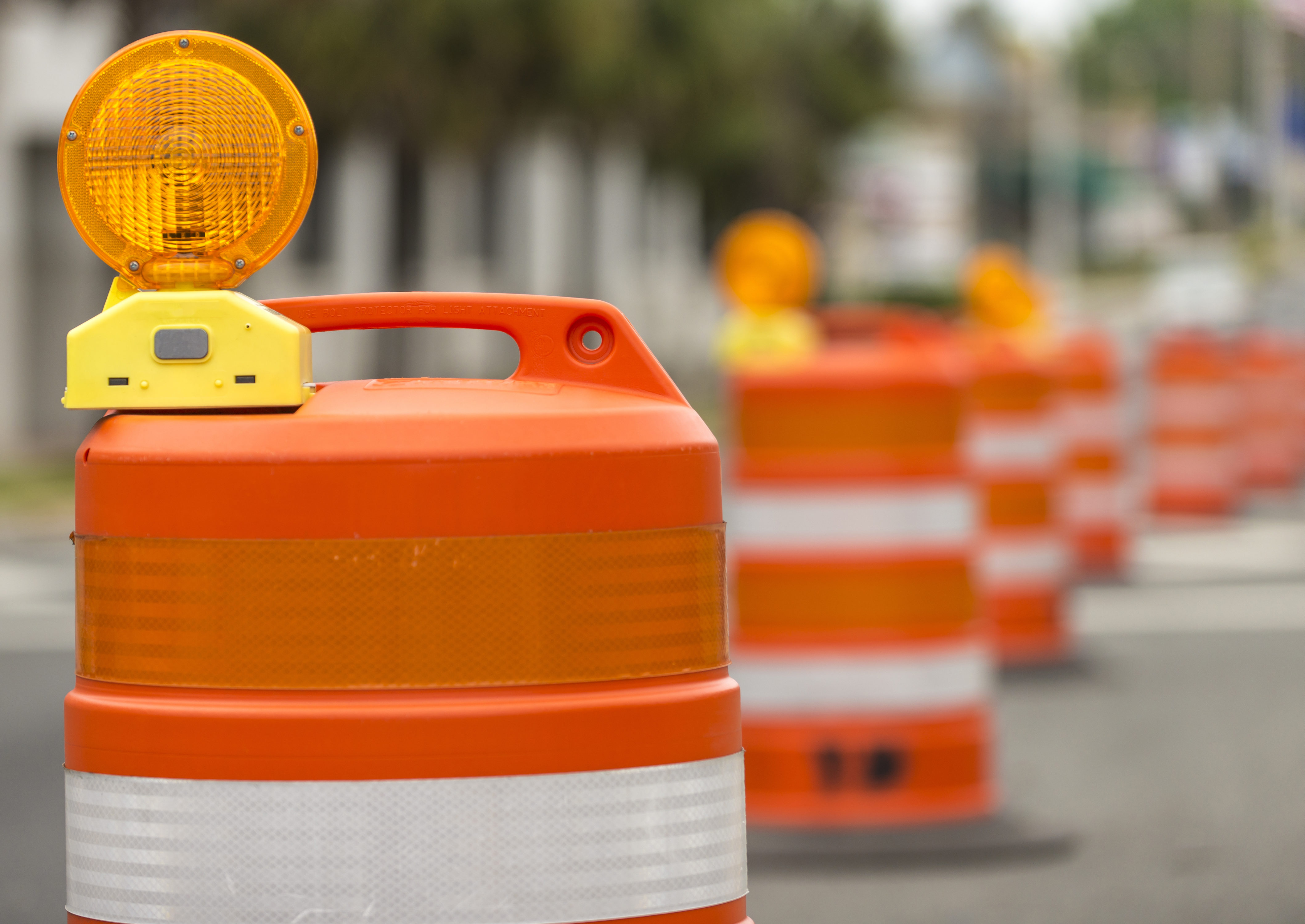 Orange traffic safety barrels with flashing lights on road
