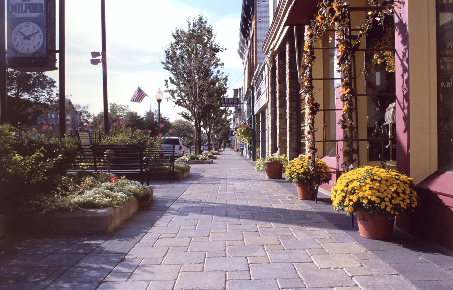 Sunny street with sidewalk, shops, and American flags