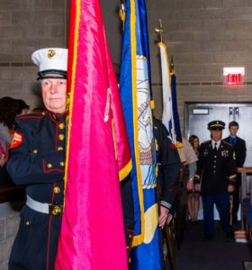 Veteran carrying flags in military ceremony.