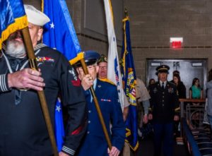 Veterans holding flags in ceremonial procession.