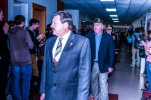 Men walking in crowded school hallway.