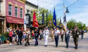 Veterans parade with flags on a sunny Main Street.