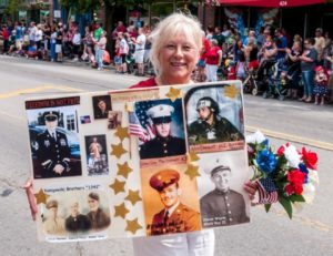 Woman holding poster honoring military service members.