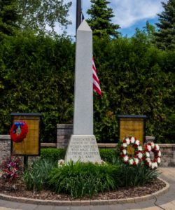 War memorial with flag and wreaths.