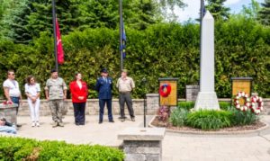 Veterans ceremony at war memorial with flags and monument.