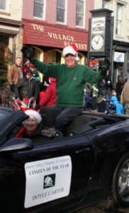 Man celebrating "Citizen of the Year" award in parade.