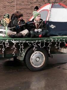 Children on parade float with camping theme.