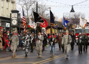 Veterans parade with flags in small town street.