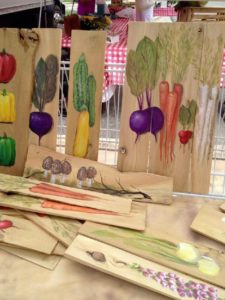 Hand-painted vegetables on wood at craft market.