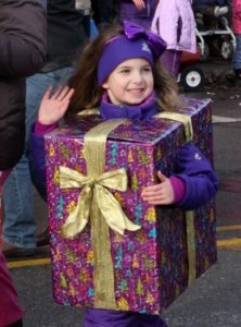 Girl dressed as a gift box with bow waving.