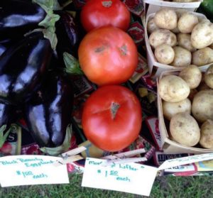 Fresh tomatoes, eggplants, and potatoes for sale.