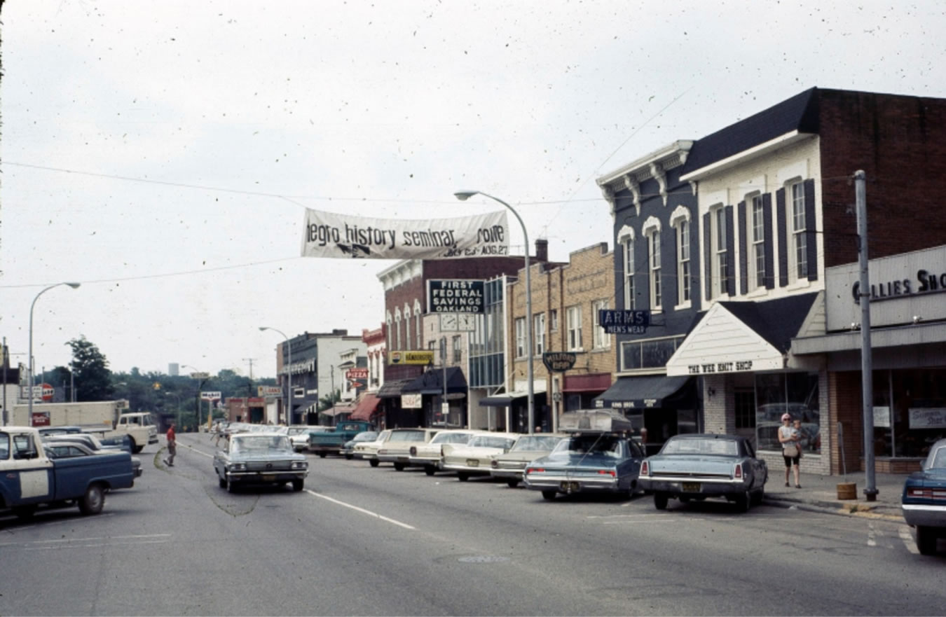 1960s American town street with vintage cars and banners