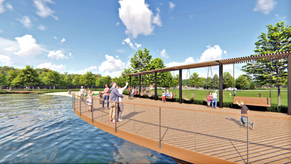 People enjoying waterfront wooden boardwalk on sunny day.